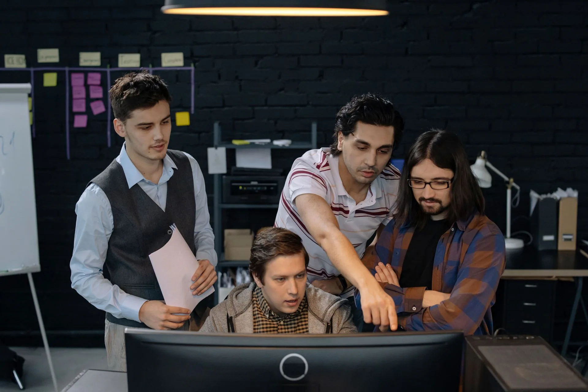 Colleagues reviewing work together at a desktop monitor